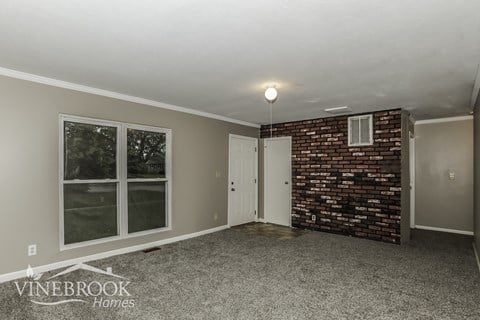 A room with a brick wall and a carpeted floor.