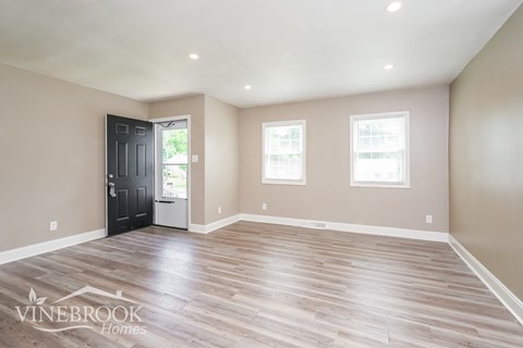 A room with a black door and two windows.