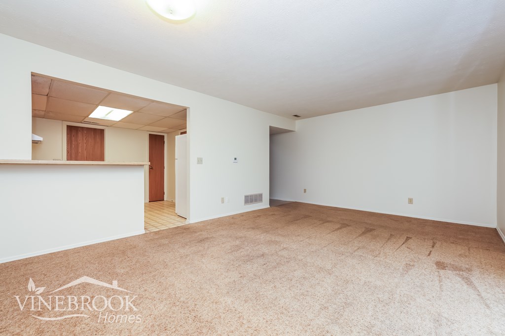 A large empty room with a carpeted floor and white walls.