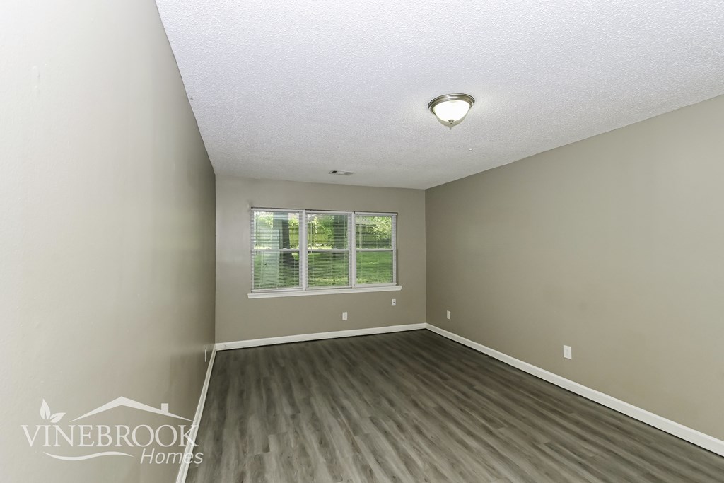A room with a window and a wooden floor.