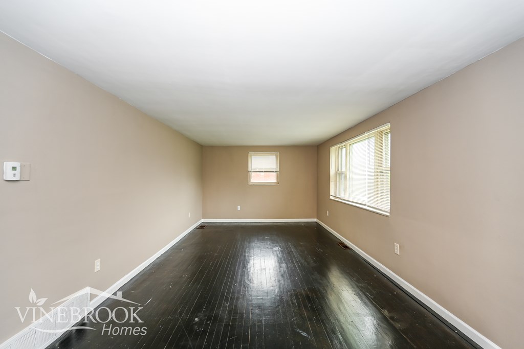 A room with a wooden floor and a window with blinds.