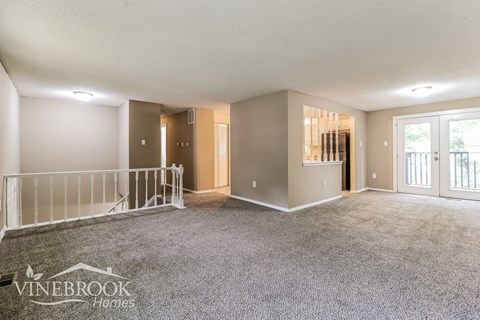 A spacious room with carpeted floor and a white ceiling.