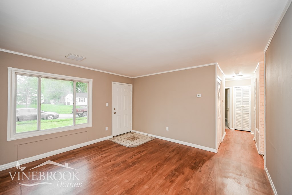 A room with wood flooring and a window overlooking a street.