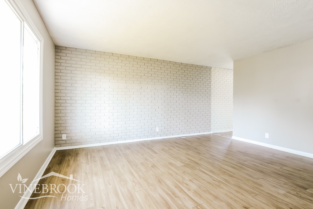 A room with wooden floors and a brick wall.