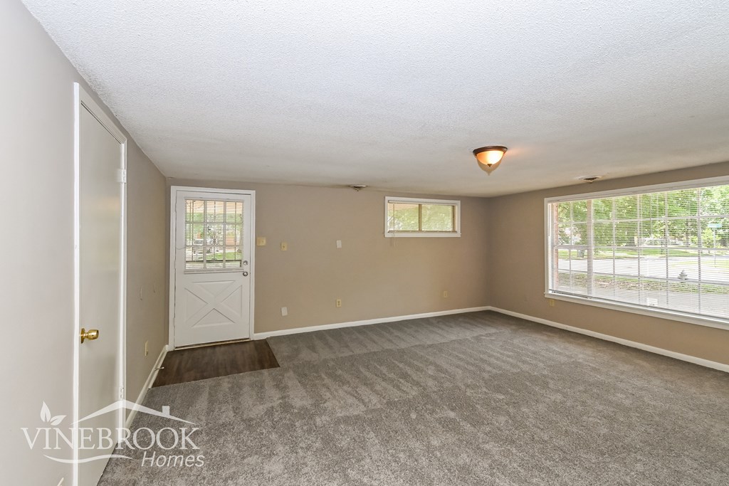 A room with a carpeted floor and a door leading to a balcony.