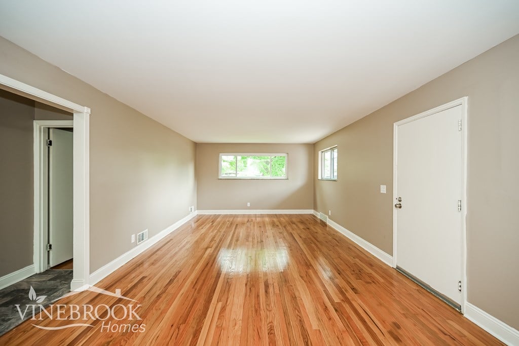 A room with wooden floors and a window with a view of trees.