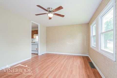 A room with a ceiling fan and wooden floors.
