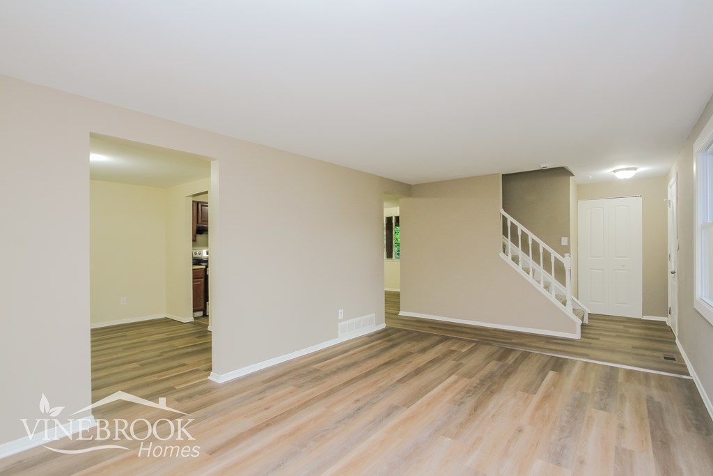 A large empty room with wooden floors and white walls.