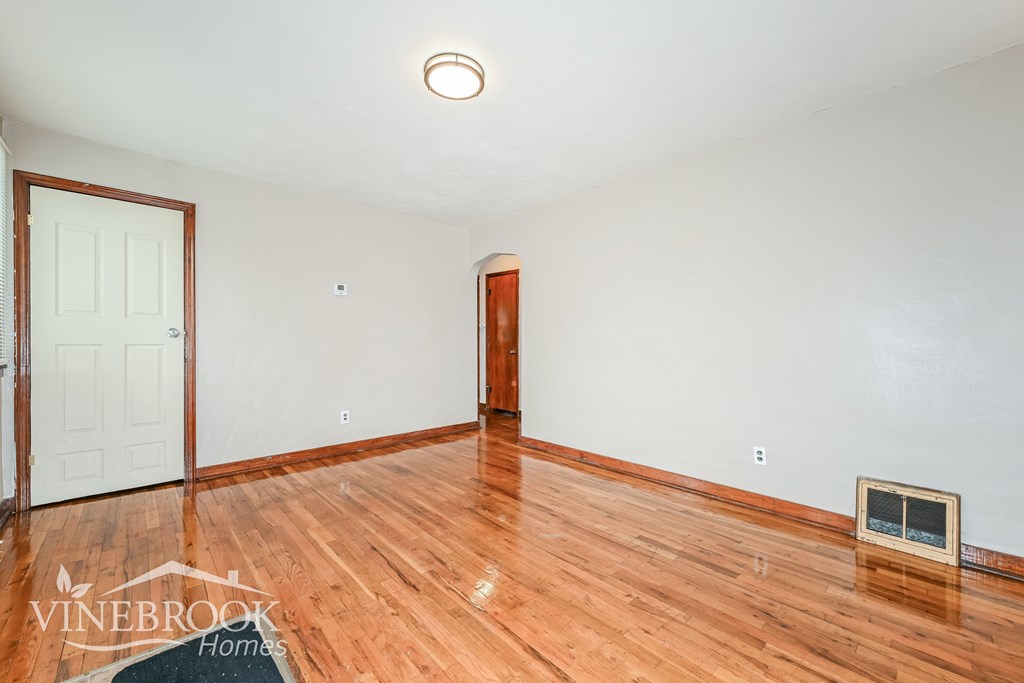 A room with wooden floors and a door on the left side.