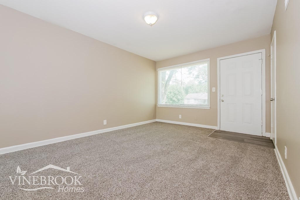 A room with a carpeted floor and a door leading to another room.