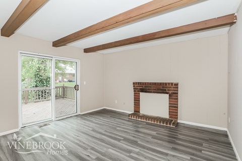 A room with a fireplace and a sliding glass door leading to a deck.