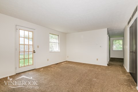 A room with a carpeted floor and a door leading outside.