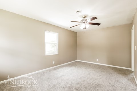 A room with a carpet floor and a ceiling fan.