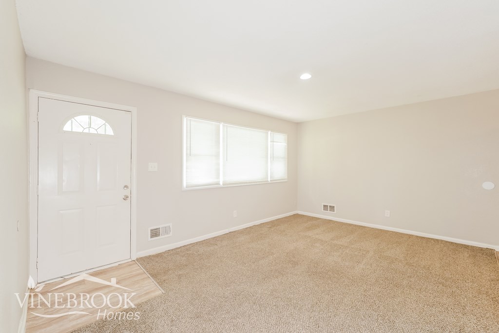 A room with a carpeted floor and a door.