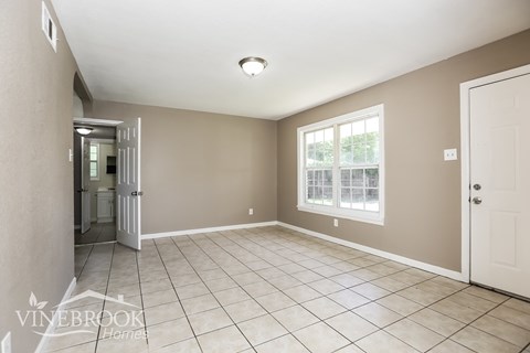A spacious room with tiled flooring and a large window.