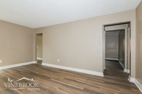 A room with wood flooring and a doorway leading to another room.