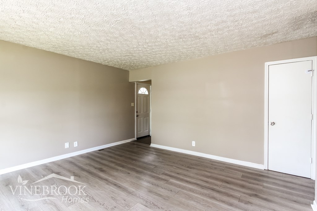 A room with a white door and a wooden floor.