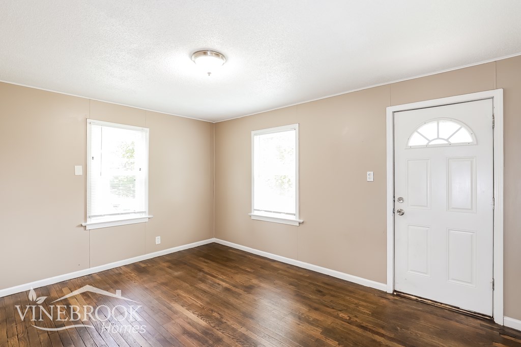 A room with a white door and two windows.