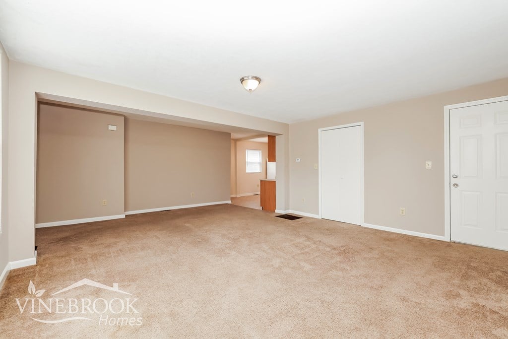 A room with beige carpet and a logo that says Vinebrook Homes.
