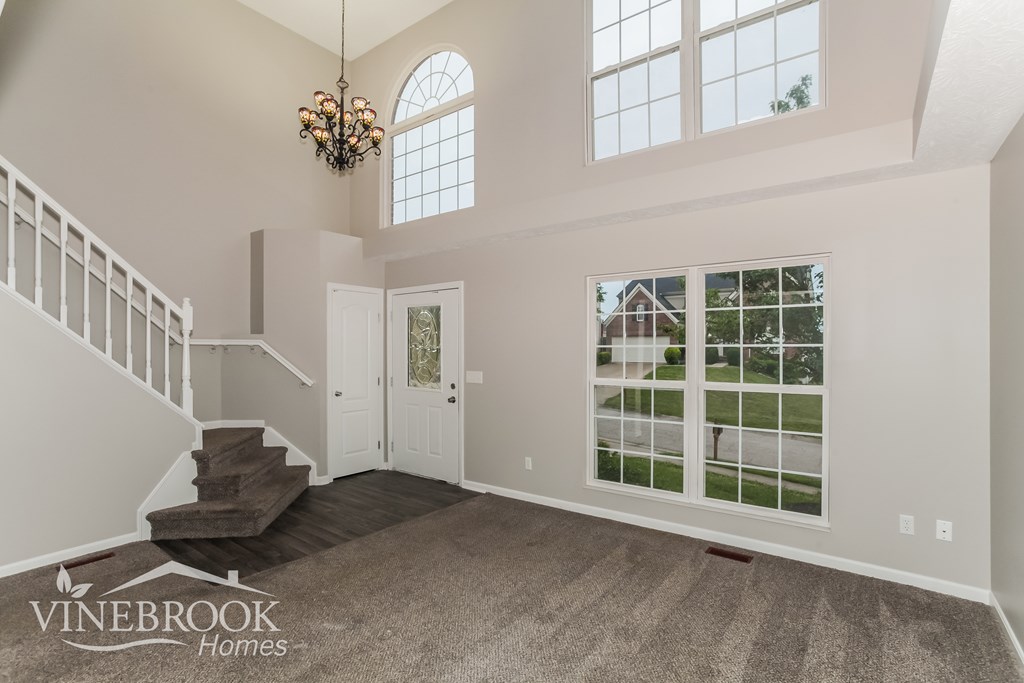 A spacious room with a staircase and a chandelier.