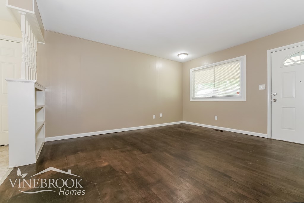 A room with wooden flooring and a window with blinds.