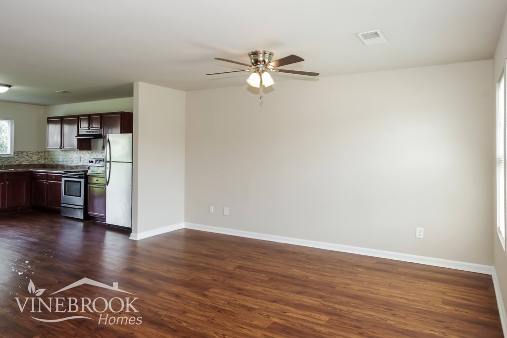 A room with a ceiling fan and wooden flooring.