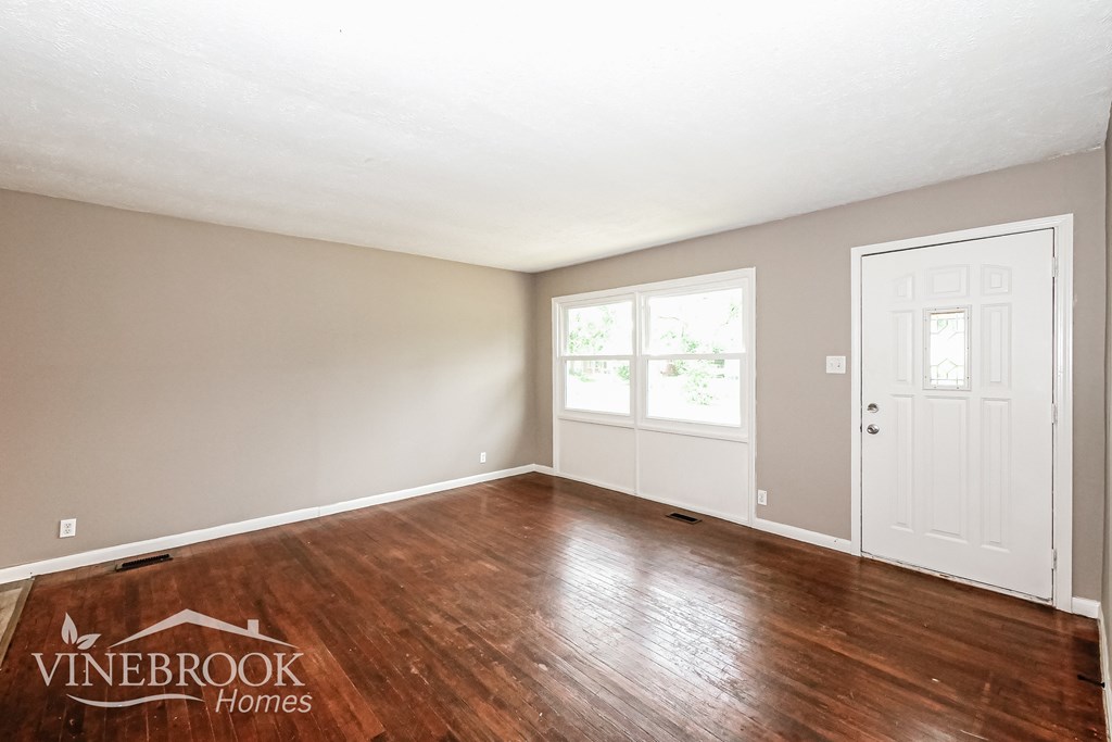 A room with a wooden floor and a door on the right side.