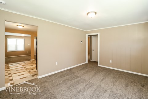 A room with a carpeted floor and a door leading to another room.