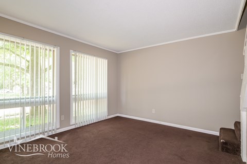 A room with a carpeted floor and a window with blinds.