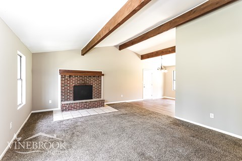 A living room with a fireplace and a carpet on the floor.