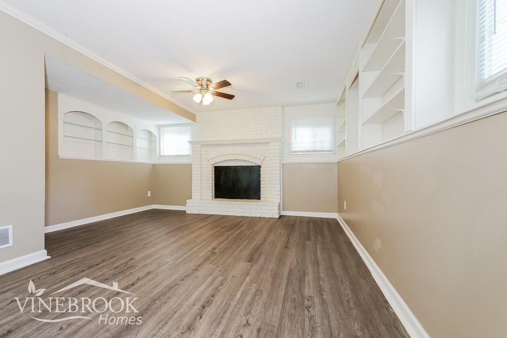 A living room with a fireplace and a ceiling fan.