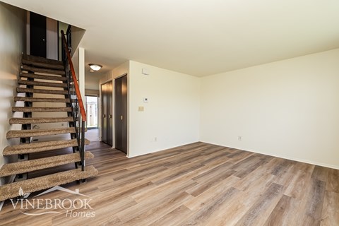 A room with wooden floors and a staircase with a wooden handrail.