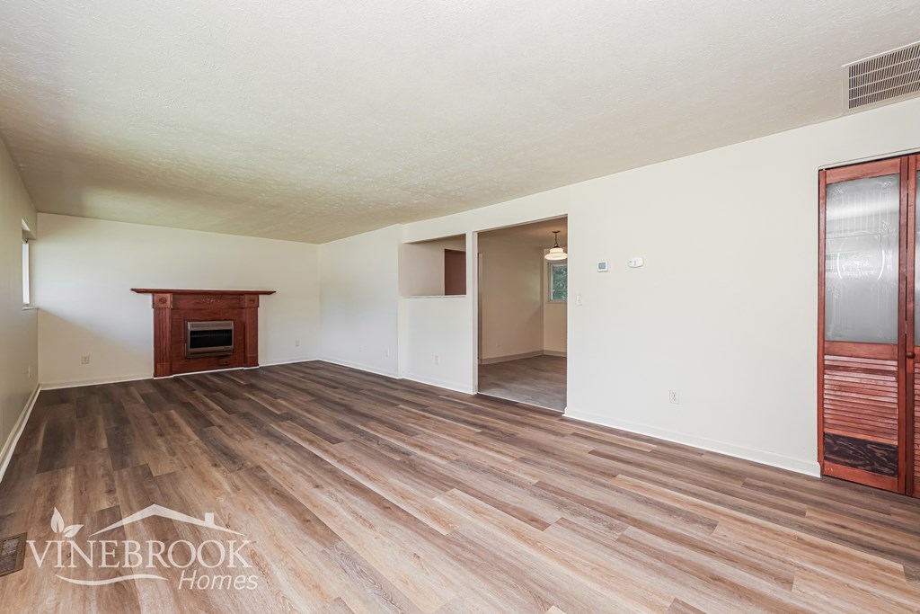 A room with wood flooring and a Vinebrook Homes logo.