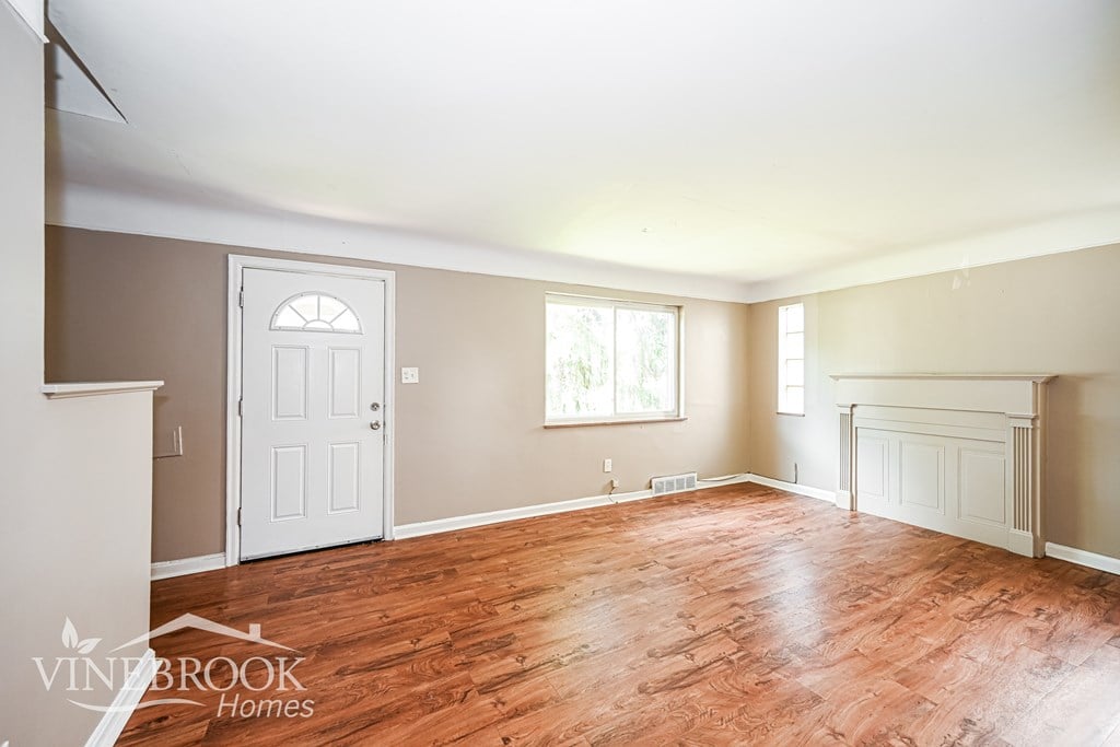 A room with wood flooring and a white door.