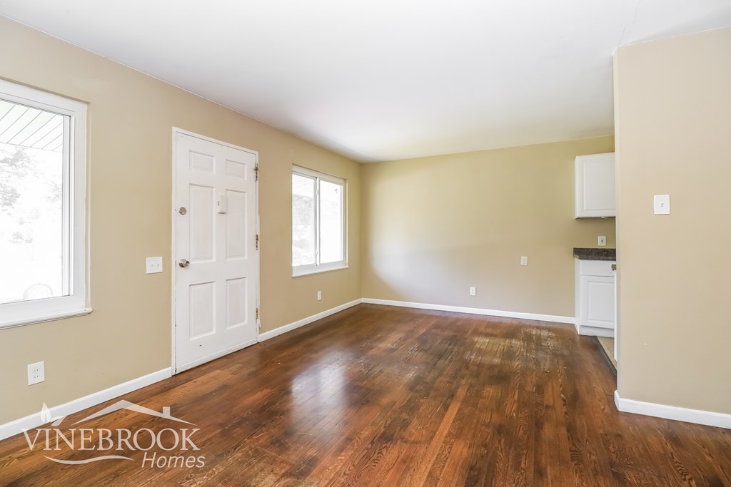 A room with wood flooring and two windows.