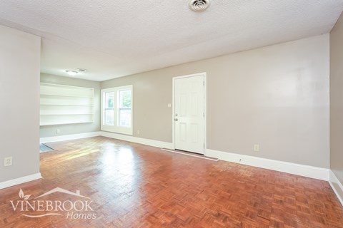 A room with a wooden floor and a door on the right side.
