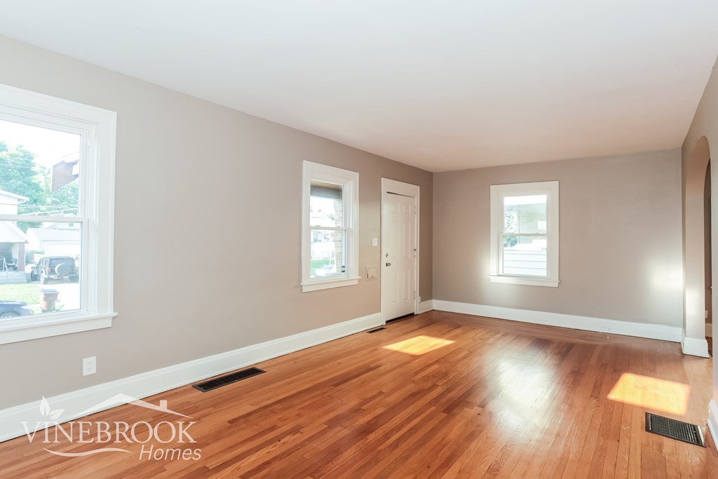 A room with wooden floors and two windows.