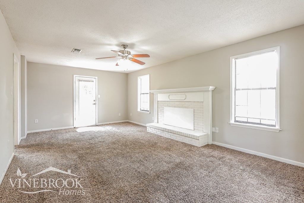 A room with a carpeted floor and a fireplace.