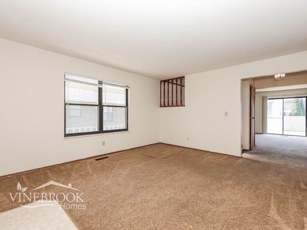 A room with a carpeted floor and a window with blinds.