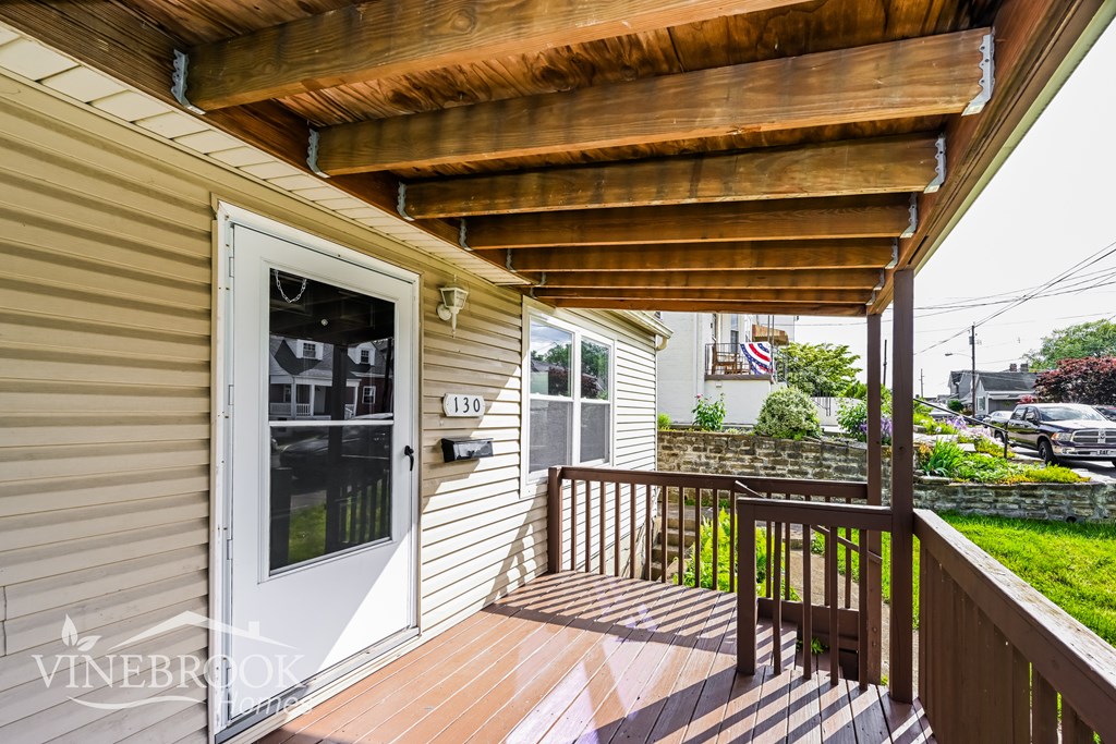 A balcony with a wooden floor and ceiling with a door and window.
