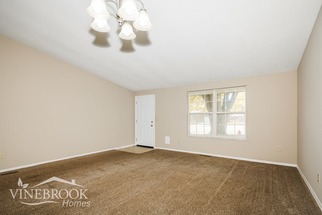 the living room of a home with carpet and a chandelier