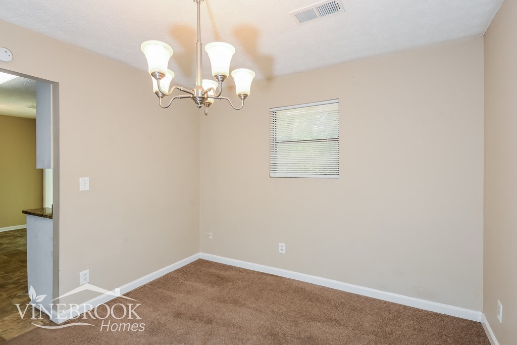 a living room with carpet and a chandelier