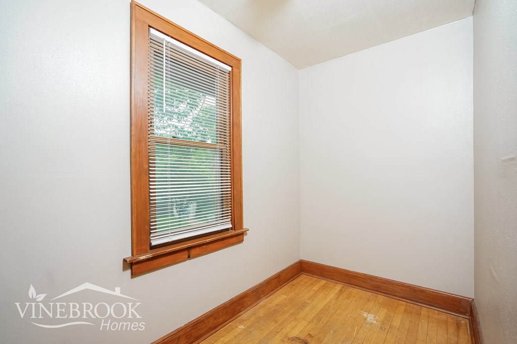 the living room of a house with a window and wood floors