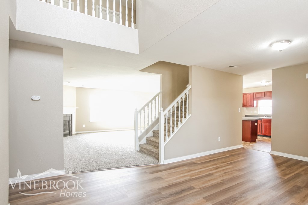 A large empty room with a staircase and a fireplace.