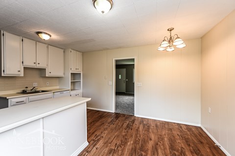 A kitchen with white cabinets and a wooden floor.