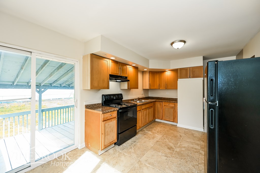 A kitchen with a black fridge and wooden cabinets.