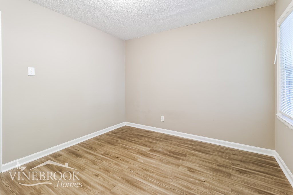 A room with wooden flooring and white walls.