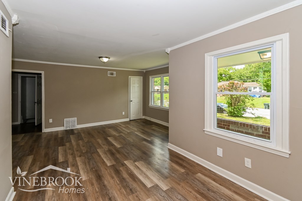 A room with a window and wooden floors is on the market with Vinebrook Homes.