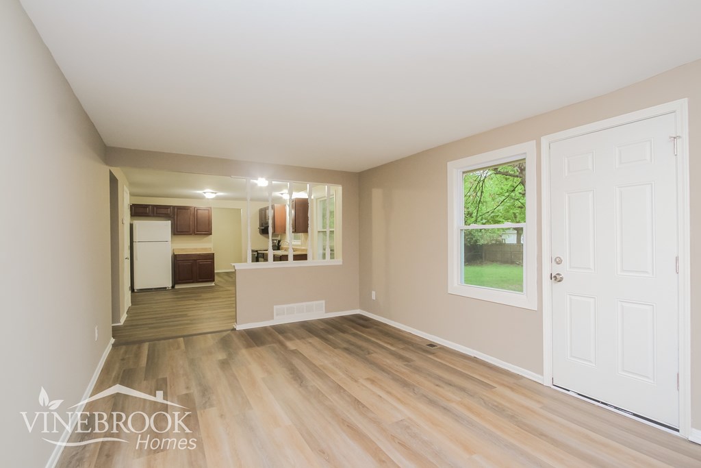 A room with a white door and a window showing greenery outside.