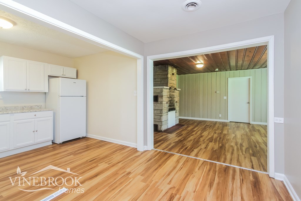 A room with wooden floors and a white refrigerator.